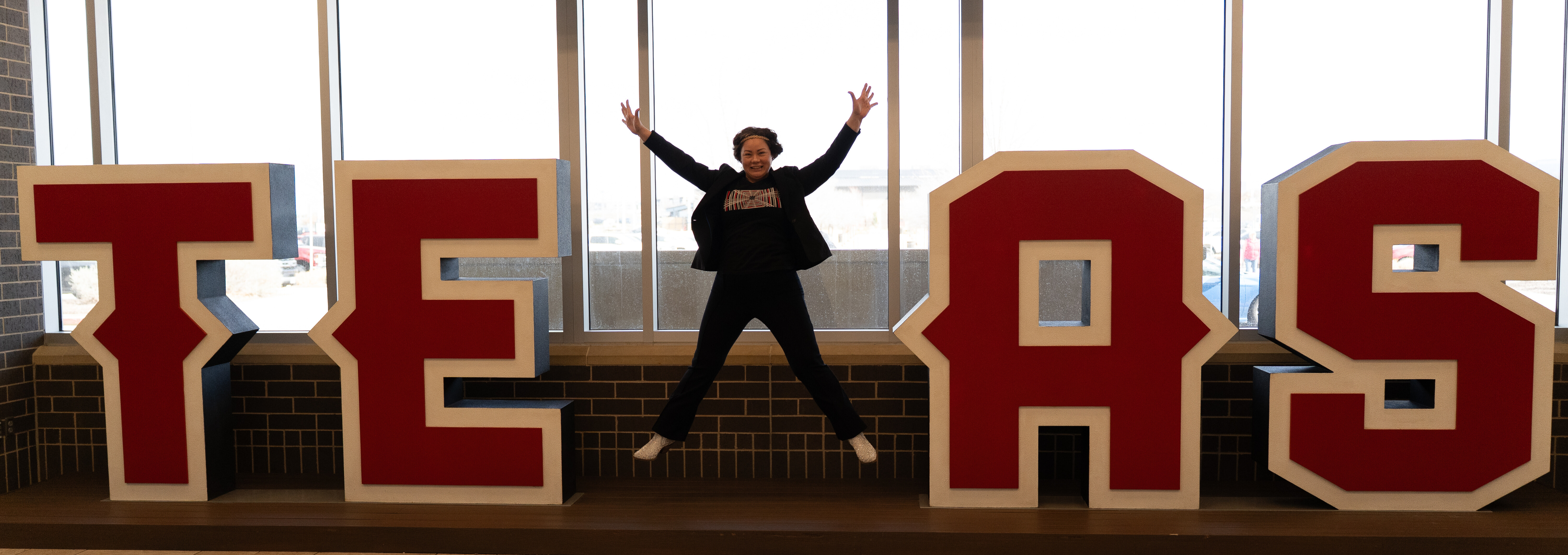 Melissa Weiner jumping in front of giant TEXAS letters